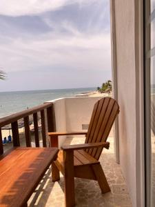 einen Holzstuhl auf dem Balkon mit Blick auf den Strand in der Unterkunft Hotel Casa Sattva- Bed & Breakfast in Rincón