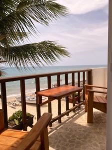 Hotel Casa Sattva- Bed & Breakfast في Rincón: طاولة خشبية وكراسي على شرفة مطلة على الشاطئ