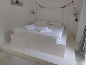 Una cama blanca con sábanas blancas y toallas. en Golden Star Praxitelous, en Agia Marina Aegina