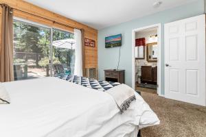 een slaapkamer met een bed en een groot raam bij The Twisted Twig - Great amenities! Patio Deck for nights under the stars & trees, and Hot Tub! in Big Bear Lake