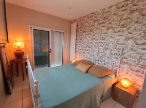 a bedroom with a bed and a brick wall at Le Havre de Paix in Céret +50 photos
