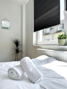 ein weißes Bett mit Handtüchern und einem Fenster in der Unterkunft Sali - R6 - Apartmenthaus, WLAN, TV in Remscheid
