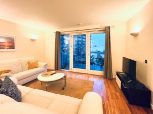 a living room with a white couch and a tv at Canary Wharf, E14 9PW, 2 Bedroom Apartment in London