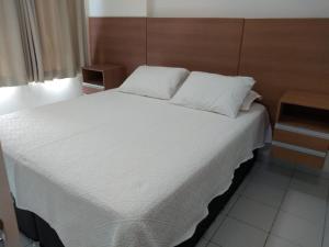 a bedroom with a white bed with a wooden headboard at Verano Praia Ponta Negra AP 1401 in Natal