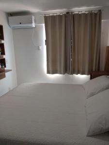 a bedroom with a white bed and a window at Verano Praia Ponta Negra AP 1401 in Natal