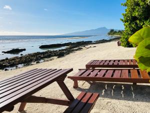 two picnic tables on a sandy beach near the ocean at moorea temae bungalow lory bord de mer in Moorea