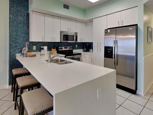 a kitchen with white cabinets and a stainless steel refrigerator at Tidewater orange Beach 209 in Orange Beach