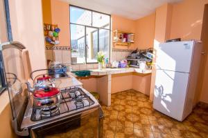 a kitchen with a stove and a white refrigerator at CAYESH Guest House in Huaraz