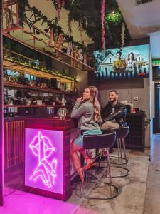 deux personnes assises dans un bar avec un signe néon dans l'établissement Audemar Boutique Hotel and Apartment Homes, à Los Angeles