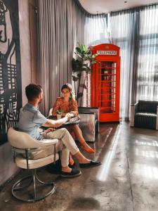 a man and woman sitting at a table with a red phone booth at Audemar Boutique Hotel and Apartment Homes in Los Angeles