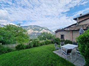 einen Tisch und Stühle auf einem Rasen mit Bergen im Hintergrund in der Unterkunft cottage lavanda e rosmarino in Lavis