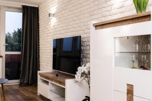 uma sala de estar com uma televisão e uma parede de tijolos em Ul SZOPY 2 APARTAMENTY ZRESETUJ SIĘ W GDAŃSKU em Gdansk