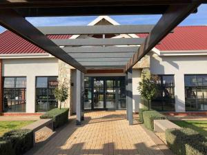 a large building with a red roof and a walkway at Luxury 1bed Serengeti OliveWood ORT Airport in Kempton Park