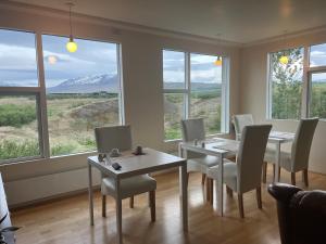 uma sala de jantar com mesas, cadeiras e janelas em Glæsibær 2 Guesthouse and horsefarm em Akureyri