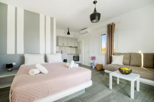 a bedroom with a pink bed and a couch at Oniropetra Apartments Mykonos in Plintri