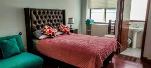 een slaapkamer met een bed met een rode deken en een stoel bij Elegante y Funcional Apartamento en zona comercial de Sopocachi in La Paz