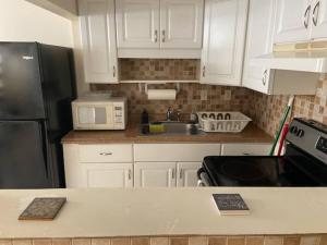 a kitchen with white cabinets and a black refrigerator at Private Rooms close to Miami Airport - Free parking - 02 in Miami