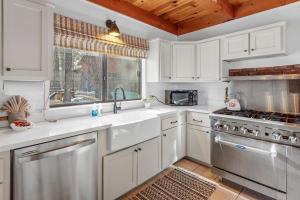 a kitchen with white cabinets and a sink and a stove at The Lakehouse Cabin - Located close to the Lake! Hot Tub, Smart TV, and WiFi! in Big Bear Lake