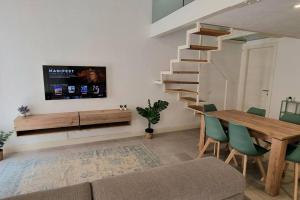 ein Wohnzimmer mit einem Tisch und einem TV an der Wand in der Unterkunft CLASSY HOMES - Acquamarina in Sanremo