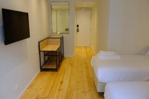 a room with two beds and a desk and a television at Liberator Rossio in Lisbon
