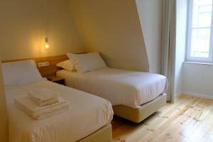 a room with two beds with white sheets and a window at Liberator Rossio in Lisbon