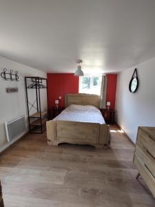 een slaapkamer met een bed en een rode muur bij Aux Berges du Mont in Pontorson