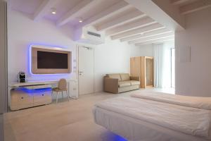 Habitación blanca con cama y TV en Unico Hotel Caorle en Caorle
