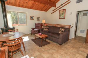 a living room with a couch and a table at Harrison's Hanger - Cozy cabin with a fairly nice view of the tree line! Wood burning fireplace! in Big Bear City