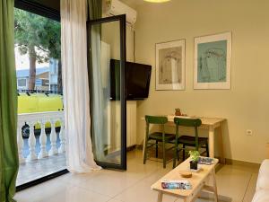 a living room with a television and a table with chairs at 100 meters from the sea in Xylokastron