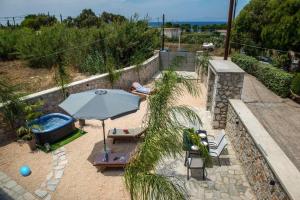 a patio with an umbrella and chairs and a pool at Odyssea Sea View Apartment one minute from the sea in Kremasti