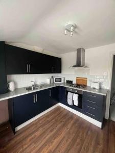 a kitchen with black cabinets and a wooden floor at Stylish 5 bedroom /7bed apartment in Seacombe