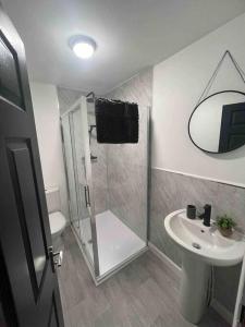 ein Bad mit einer Dusche und einem Waschbecken in der Unterkunft Stylish 5 bedroom /7bed apartment in Seacombe