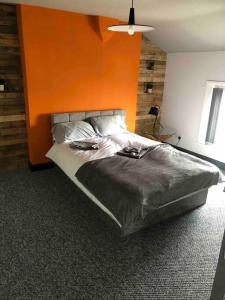 a bedroom with a large bed with an orange wall at Stylish 5 bedroom /7bed apartment in Seacombe