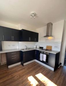 eine Küche mit schwarzen und weißen Geräten und Holzböden in der Unterkunft Stylish 5 bedroom /7bed apartment in Seacombe