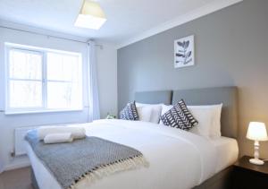 a white bedroom with a large white bed and a window at Central Peaceful Home with Parking, Wi-Fi and Garden in Stafford