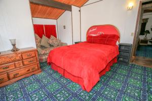 a bedroom with a red bed and a couch at Cardinal Ridge - Rustic cabin with stellar outdoor features! Wrap-around deck and large yard! in Big Bear City