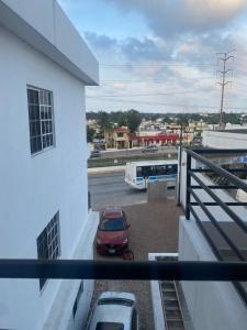 une voiture rouge garée sur un parking avec un bus dans l'établissement Hotel Magnolia, à Tampico