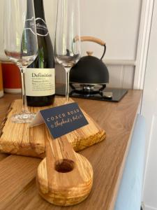 a bottle of wine and two glasses on a table at Coachroad Shepherds Huts in Petworth