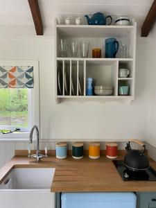 a kitchen with a sink and a counter with dishes at Coachroad Shepherds Huts in Petworth