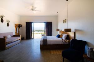 a bedroom with a bed and a couch and a window at Finca San Sebastian in Valle de Guadalupe