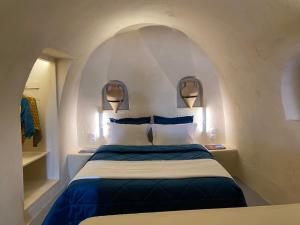 a bedroom with a large bed with blue and white pillows at Amphora Villas Oia Santorini in Foinikiá