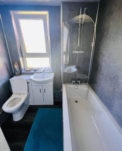 La salle de bains est pourvue de toilettes, d'un lavabo et d'une baignoire. dans l'établissement Park Road Holiday Home, à Rosyth
