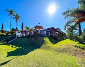 una colina de césped con una casa y palmeras en Casa de campo c churrasqueira e Wi-Fi Itatiba SP en Itatiba