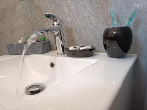 a sink with a faucet and a cup of tooth brushes at Clio's House - Mondello in Mondello +44 photos