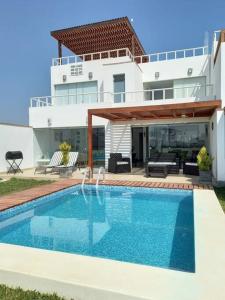 a swimming pool in front of a house at Casa de Playa con Piscina Exclusiva in Pisco