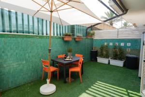 a patio with a table and chairs and an umbrella at Lotus - Apartment sul mare con giardino in Lido di Ostia