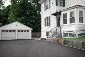 a white house with a driveway and a garage at Your Cozy and Relaxing Retreat in Woburn