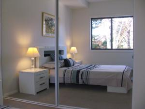 a bedroom with a bed and a window and a mirror at Quiet apartment adjacent Parliament House in Kingston 