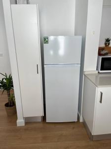 a white refrigerator in a kitchen with a microwave at HOUSE NEXT TO THE THEATER in Évora