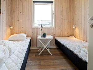 two beds in a room with a table and a window at Holiday home Harboøre XXIII in Harboør